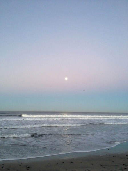 The full moon sets and the sun rises at Carlsbad Beach, San Diego County, California